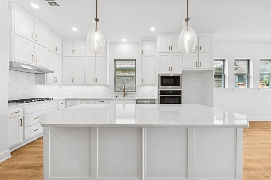 Kitchen with light wood-style floors, white cabinets, backsplash, and stainless steel appliances Kitchen with light wood-style floors, white cabinets, backsplash, and stainless steel appliances