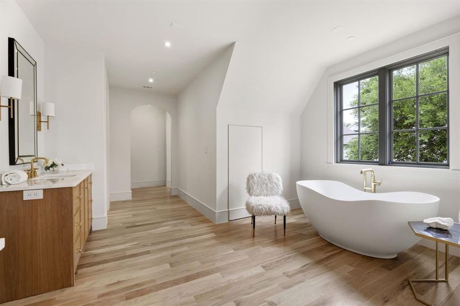 Freestanding soaking tub with gold-finish fixtures and a large grid-pane window Freestanding soaking tub with gold-finish fixtures and a large grid-pane window