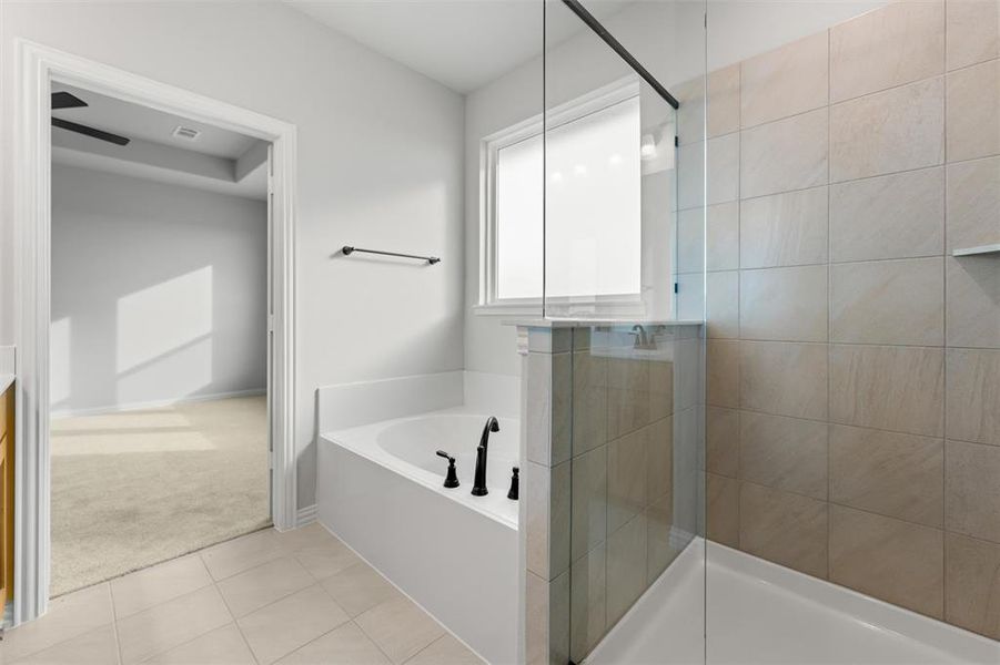 Full bath with a garden tub, tiled shower, light tile patterned flooring, and light colored carpet Full bath with a garden tub, tiled shower, light tile patterned flooring, and light colored carpet