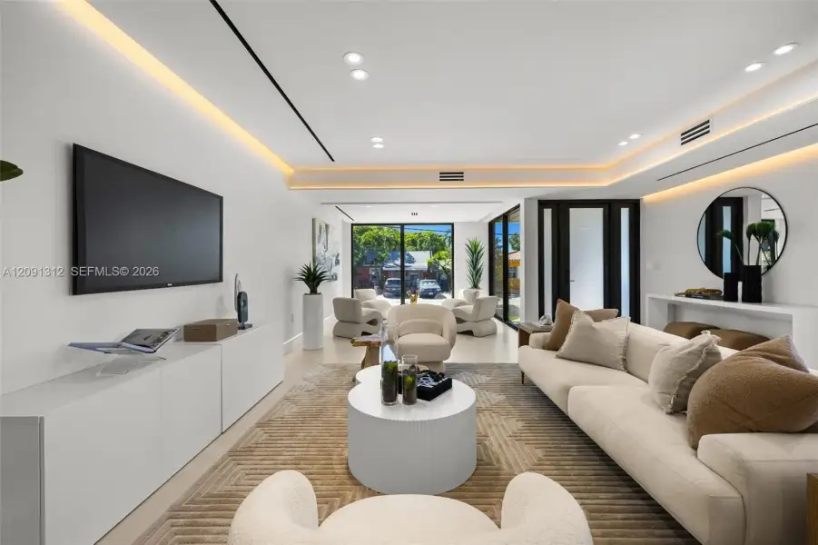 Living area featuring recessed LED cove lighting, recessed ceiling lighting, large-format tile flooring, and floor-to-ceiling glass panel doors Living area featuring recessed LED cove lighting, recessed ceiling lighting, large-format tile flooring, and floor-to-ceiling glass panel doors