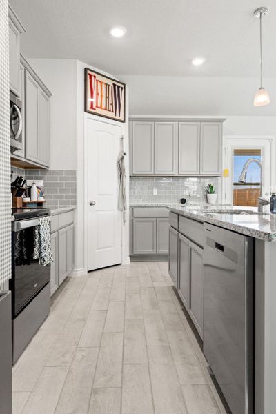 Kitchen with gray cabinetry, backsplash, hanging light fixtures, light stone counters, and recessed lighting