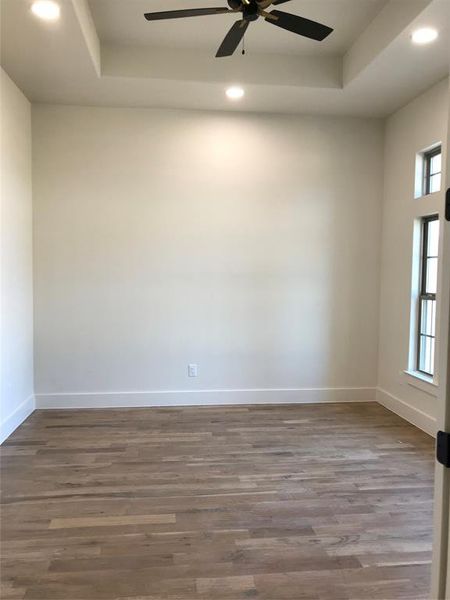 Empty room with recessed lighting, a raised ceiling, dark wood-style floors, and ceiling fan