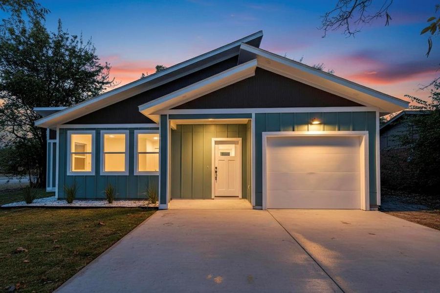 View of front of property with board and batten siding, driveway, a garage, and a yard View of front of property with board and batten siding, driveway, a garage, and a yard