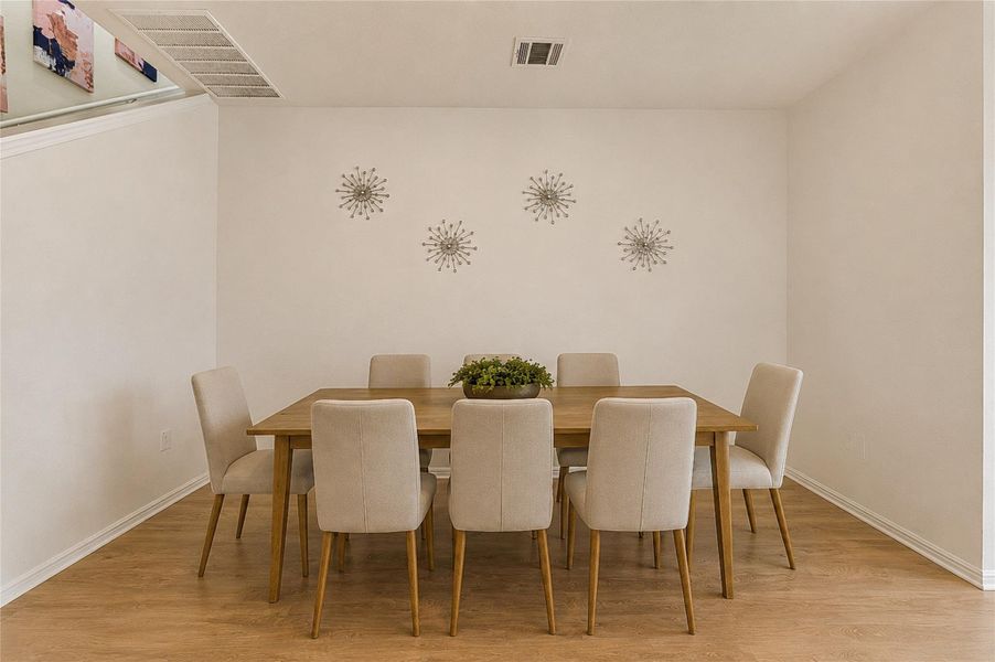 Dining area features warm wood flooring and tasteful wall decor, perfect for gatherings.