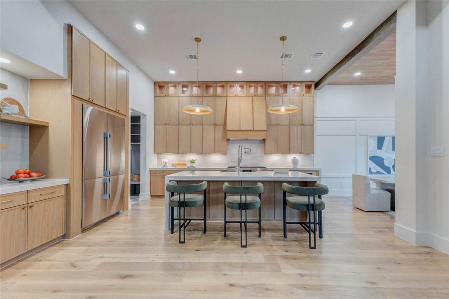 A closer look at the impressive kitchen design highlights the extensive cabinetry, integrated lighting, and full quartz backsplash. The central island offers ample prep space and seating, combining functionality with refined style.