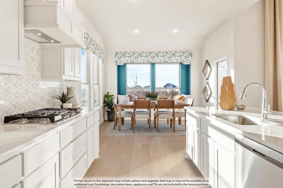 Open kitchen with white cabinets, gas cooktop, and light wood floors leading to a dining area with large windows. Open kitchen with white cabinets, gas cooktop, and light wood floors leading to a dining area with large windows.