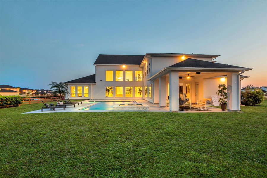 Architectural lines frame a stunning rear elevation where illuminated interiors overlook the pool, spa, and manicured grounds, creating a captivating backdrop for evening gatherings.