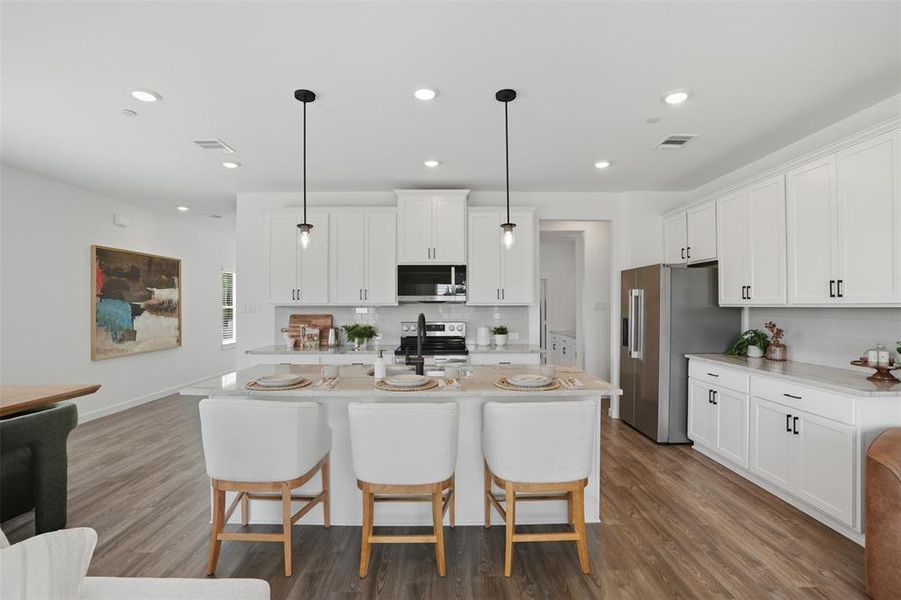 Kitchen featuring a breakfast bar, pendant lighting, white cabinetry, tasteful backsplash, and recessed lighting Kitchen featuring a breakfast bar, pendant lighting, white cabinetry, tasteful backsplash, and recessed lighting
