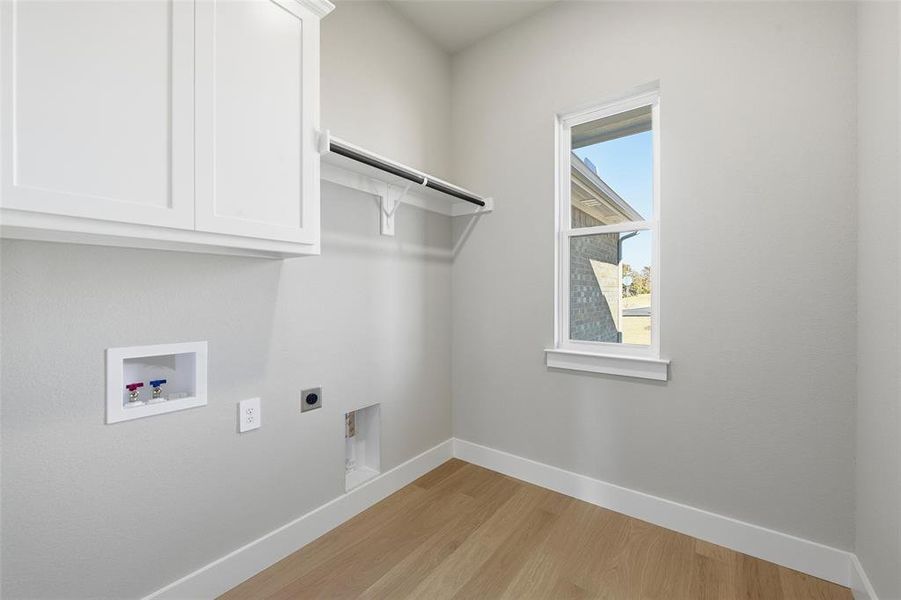 Laundry room with washer hookup, light wood-style flooring, cabinet space, and electric dryer hookup Laundry room with washer hookup, light wood-style flooring, cabinet space, and electric dryer hookup