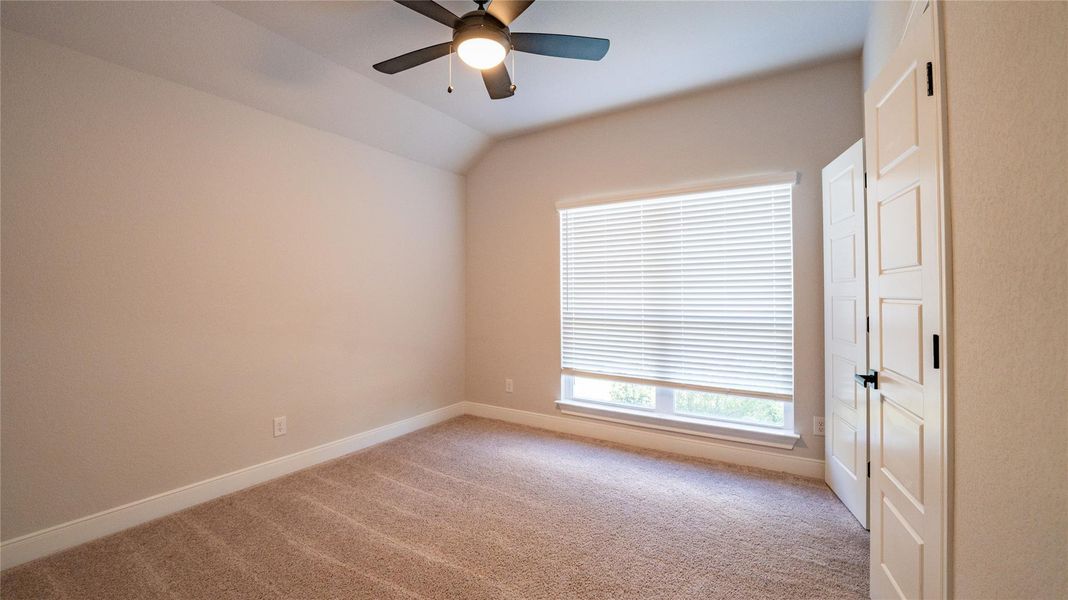 Unfurnished room with light colored carpet, a ceiling fan, and vaulted ceiling Unfurnished room with light colored carpet, a ceiling fan, and vaulted ceiling