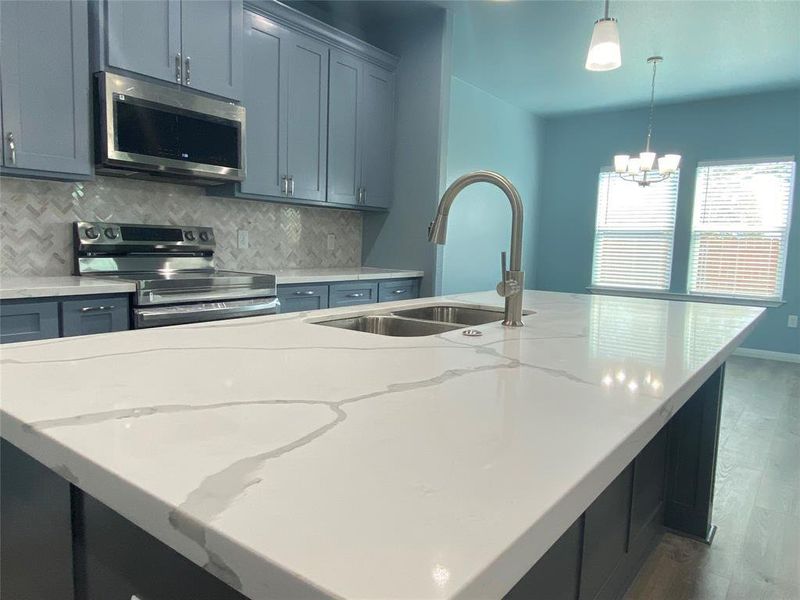A well-appointed kitchen showcases a spacious island with a dual-basin sink and gleaming stainless steel appliances. A well-appointed kitchen showcases a spacious island with a dual-basin sink and gleaming stainless steel appliances.