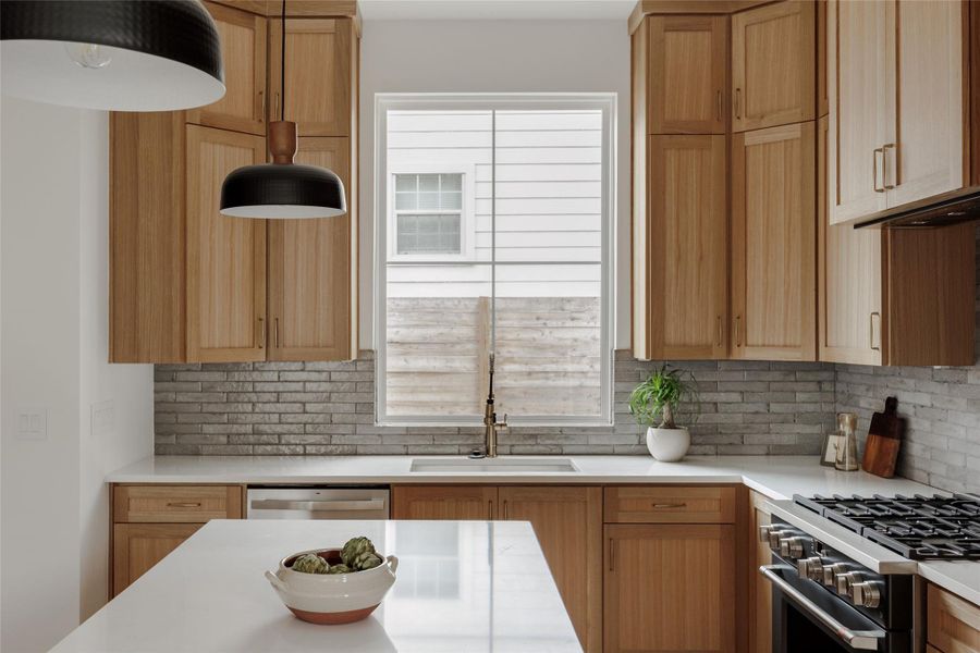 Kitchen featuring stainless steel appliances, tasteful backsplash, and light stone counters