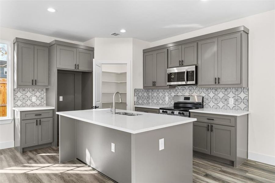 Kitchen with gray cabinets, stainless steel appliances, decorative backsplash, and recessed lighting Kitchen with gray cabinets, stainless steel appliances, decorative backsplash, and recessed lighting
