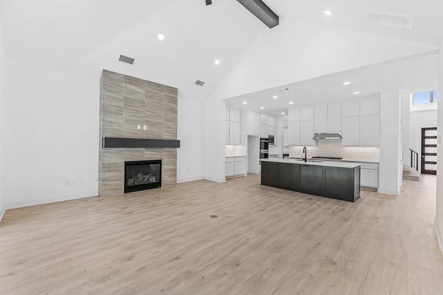 Kitchen featuring open floor plan, white cabinetry, beamed ceiling, high vaulted ceiling, and light wood finished floors
