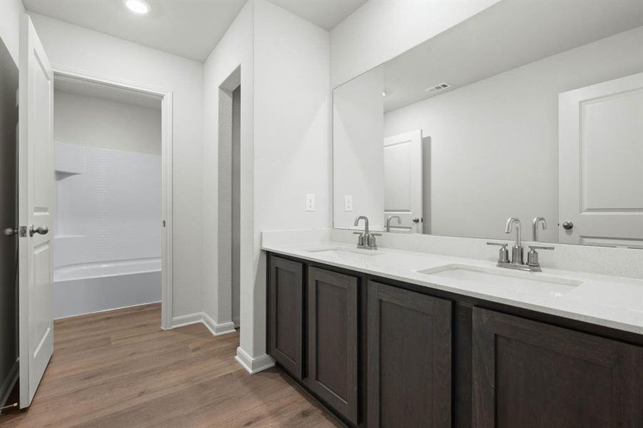 Bathroom with dark wood-type flooring, double vanity, and shower combination Bathroom with dark wood-type flooring, double vanity, and shower combination