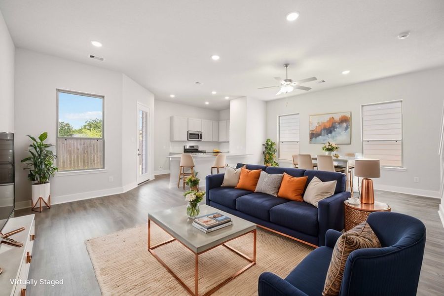 Open-concept living room with navy sofa, dining area, and kitchen with white cabinets