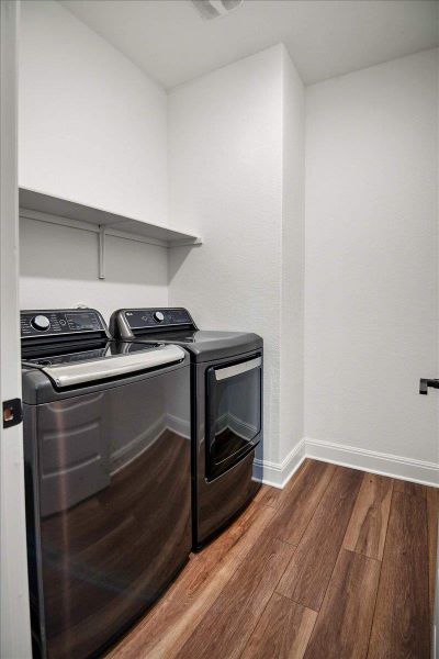 Functional laundry room equipped with modern appliances and durable wood flooring.