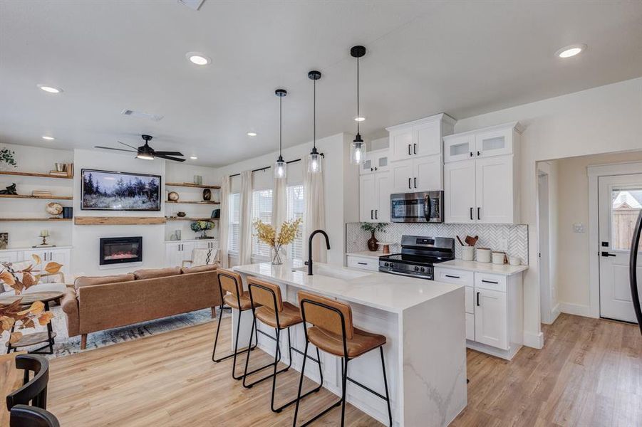 Kitchen featuring pendant lighting, light stone countertops, white cabinets, a breakfast bar, and glass insert cabinets Kitchen featuring pendant lighting, light stone countertops, white cabinets, a breakfast bar, and glass insert cabinets