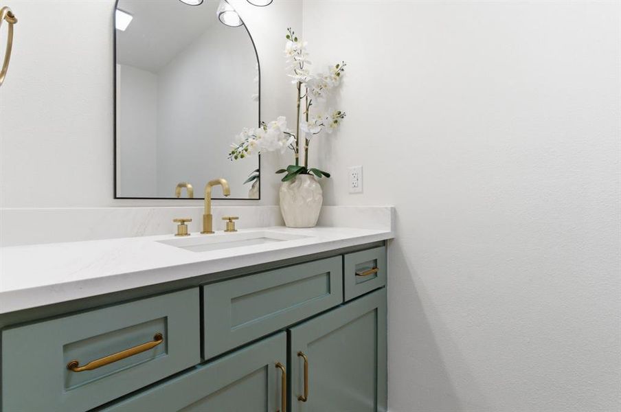 Bathroom vanity featuring a white countertop, an integrated sink, and a gold-toned faucet Bathroom vanity featuring a white countertop, an integrated sink, and a gold-toned faucet