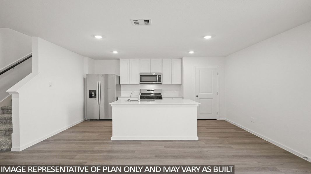 A contemporary kitchen space boasts an island and stainless steel appliances, ready for culinary endeavors.