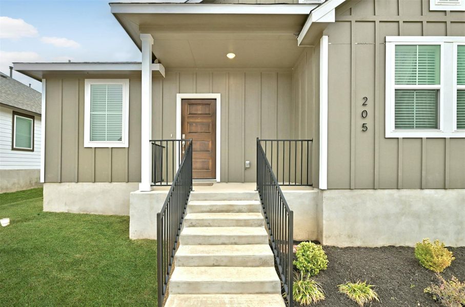 Doorway to property with board and batten siding and a yard Doorway to property with board and batten siding and a yard