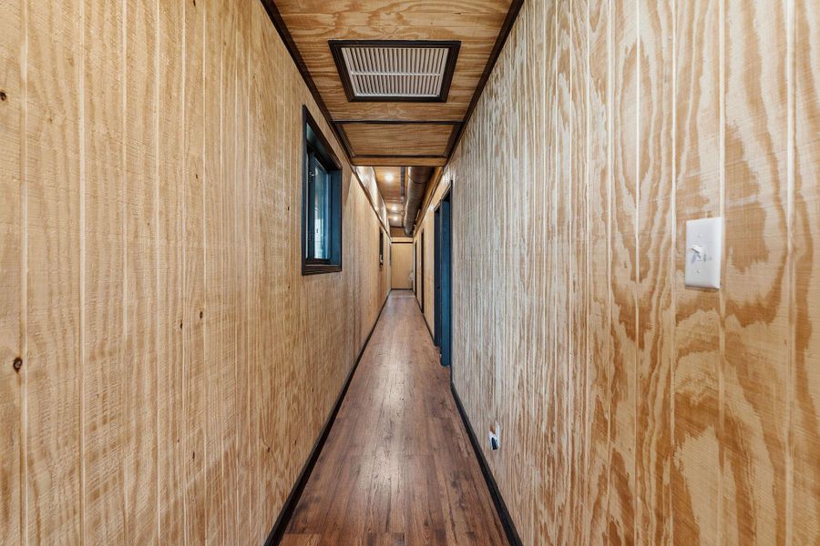 A long, inviting hallway showcases warm wood paneling, leading to private spaces.