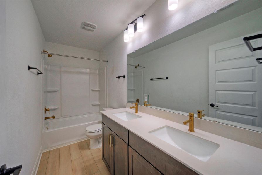 Gold fixtures accent the clean lines of a dual vanity under a large mirror. Gold fixtures accent the clean lines of a dual vanity under a large mirror.
