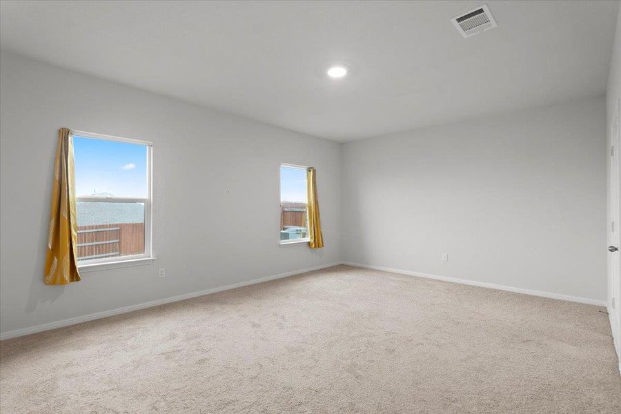 Spacious room featuring neutral carpeting, light-toned walls, and recessed lighting
