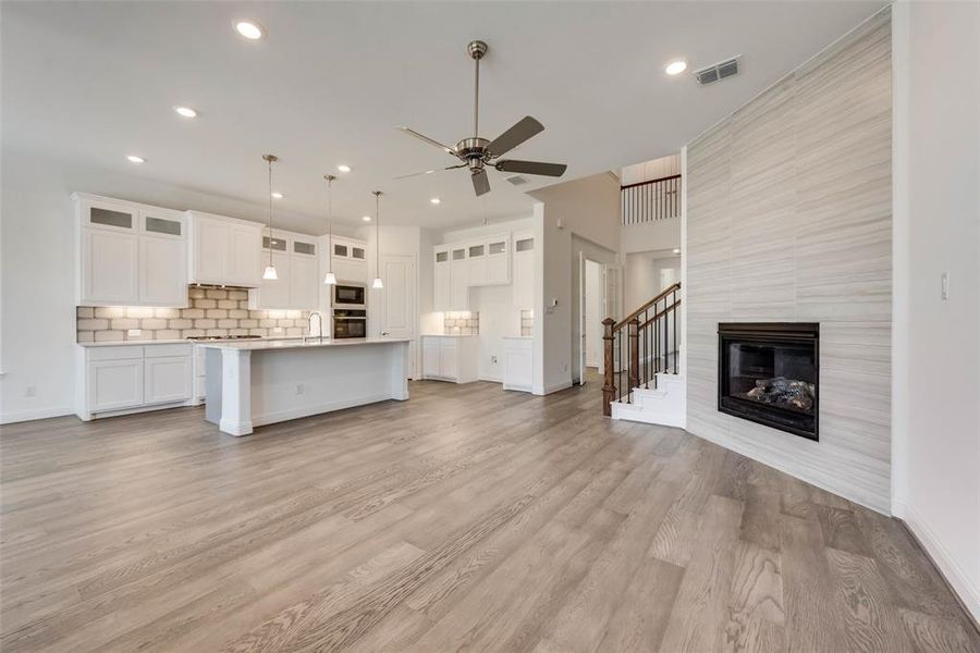 Unfurnished living room with ceiling fan, a fireplace, and light hardwood / wood-style floors