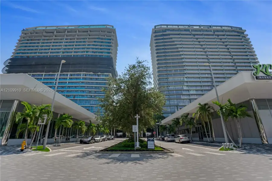 High-rise residential towers featuring glass-curtain facades, expansive balconies, integrated ground-level retail, and professionally landscaped paved entryways