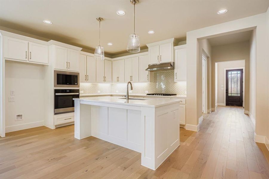 Kitchen featuring decorative backsplash, white cabinets, appliances with stainless steel finishes, recessed lighting, and decorative light fixtures