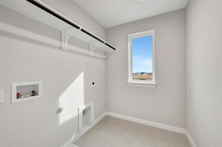 Laundry area with electric dryer hookup, washer hookup, and light tile patterned flooring