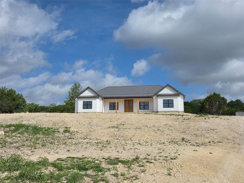 Modern farmhouse exterior with white siding, a gray metal roof, and dark-framed windows