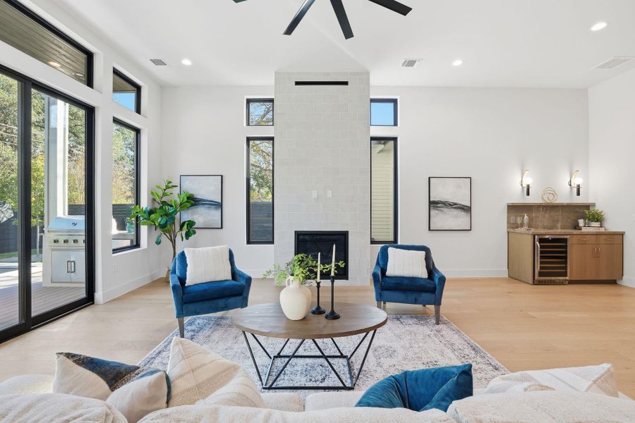 Living area featuring beverage cooler, light wood-type flooring, a fireplace, recessed lighting, and ceiling fan