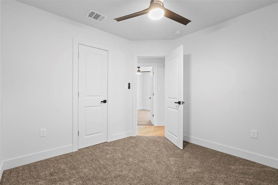 Unfurnished bedroom with light carpet and ceiling fan