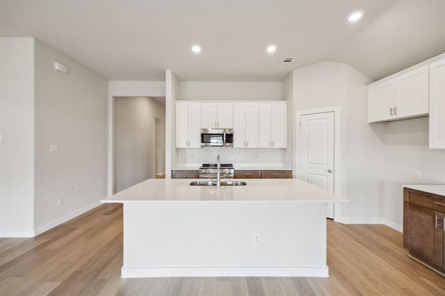 Another view of the kitchen featuring the island with a breakfast bar