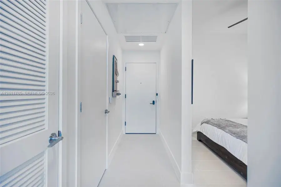 Entryway featuring smooth tile flooring, clean white walls, a recessed ceiling light, and louvered closet doors