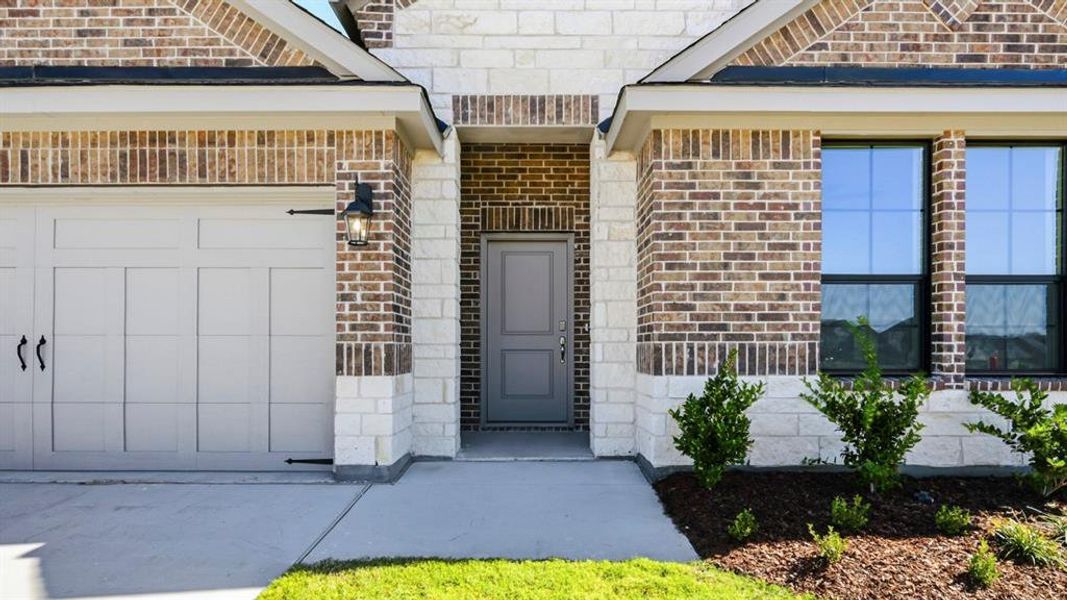 Doorway to property with brick siding and an attached garage