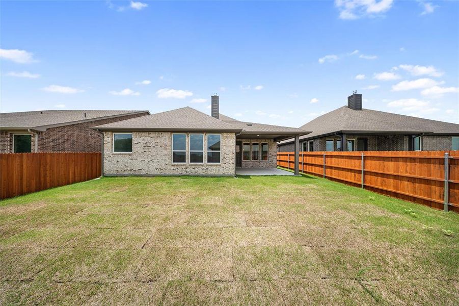 Rear view of property featuring brick siding, a fenced backyard, a patio area, and a chimney