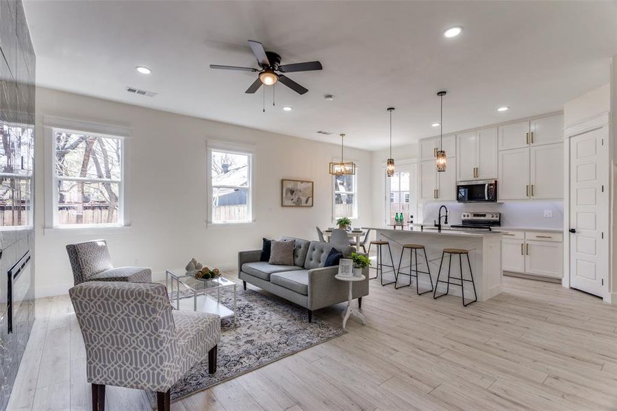 Living area featuring light wood-style flooring, visible vents, a wealth of natural light, and ceiling fan