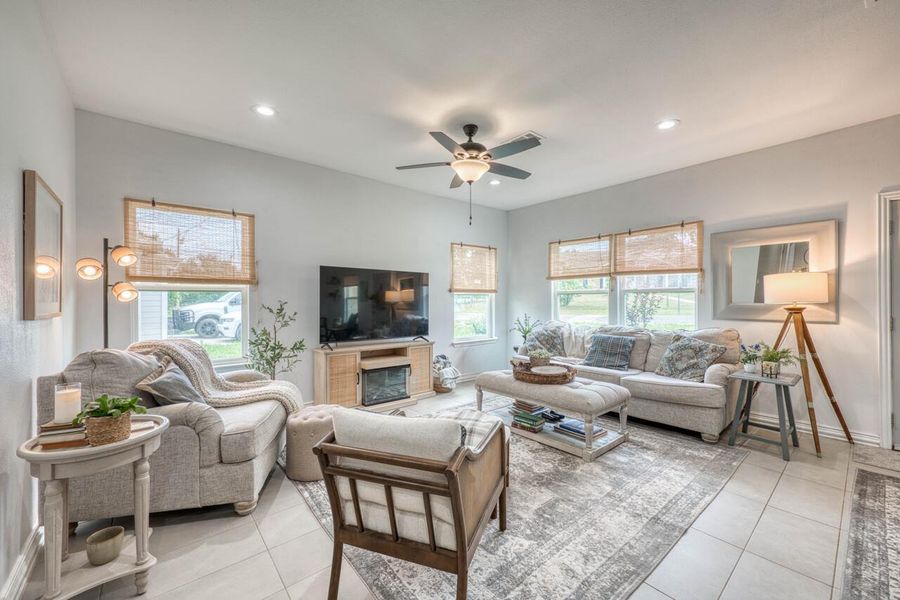Spacious living area featuring light-toned tile flooring, recessed lighting, and a ceiling fan