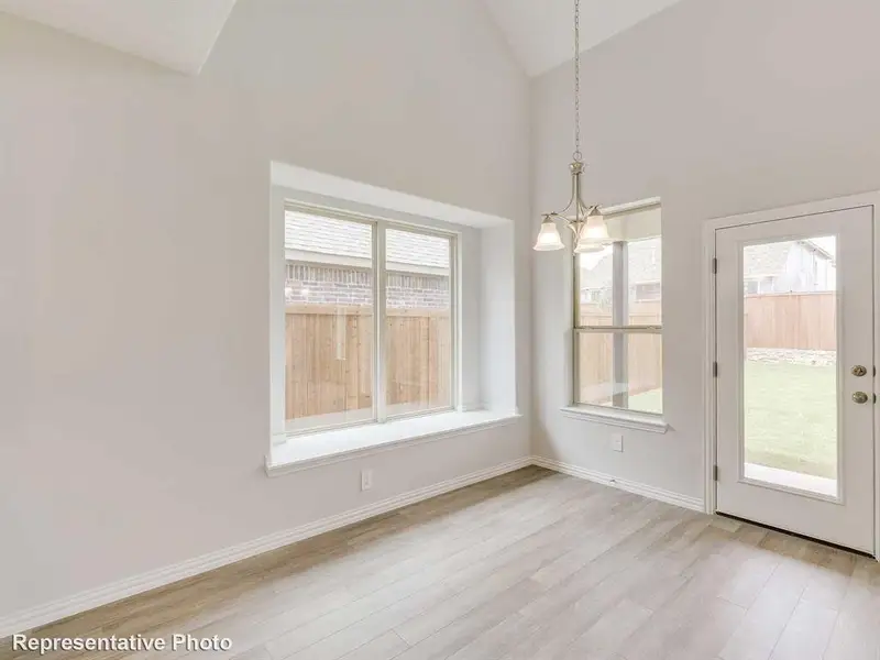 This room features high vaulted ceilings, light-colored flooring, and large windows with a deep sill