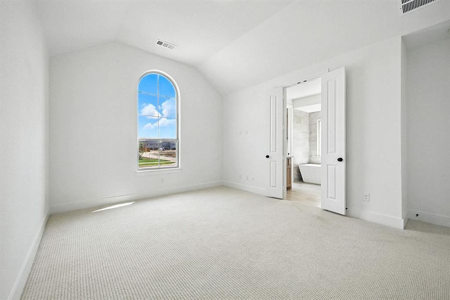 Unfurnished bedroom with light carpet and vaulted ceiling Unfurnished bedroom with light carpet and vaulted ceiling