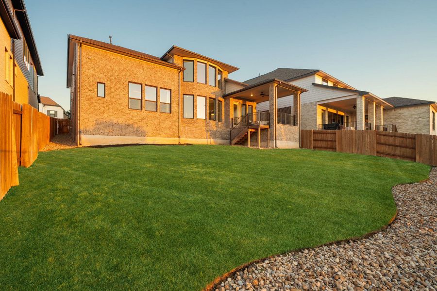 Spacious backyard featuring a manicured lawn, a gravel border, and a privacy fence Spacious backyard featuring a manicured lawn, a gravel border, and a privacy fence