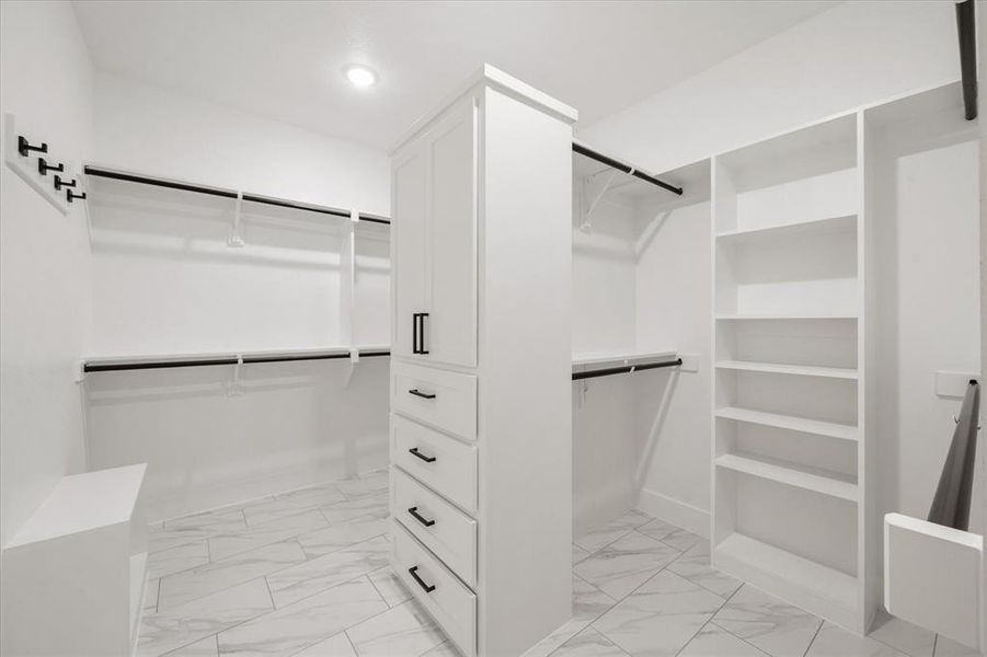 Custom closet system featuring white cabinetry, multiple hanging rods, built-in shelving, and drawer storage
