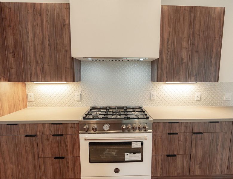 Culinary delights await in this modern kitchen with rich wood cabinetry and elegant backsplash. It features this Bertazzoni oven Culinary delights await in this modern kitchen with rich wood cabinetry and elegant backsplash. It features this Bertazzoni oven