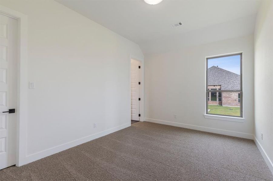 Carpeted spare room featuring vaulted ceiling and a healthy amount of sunlight