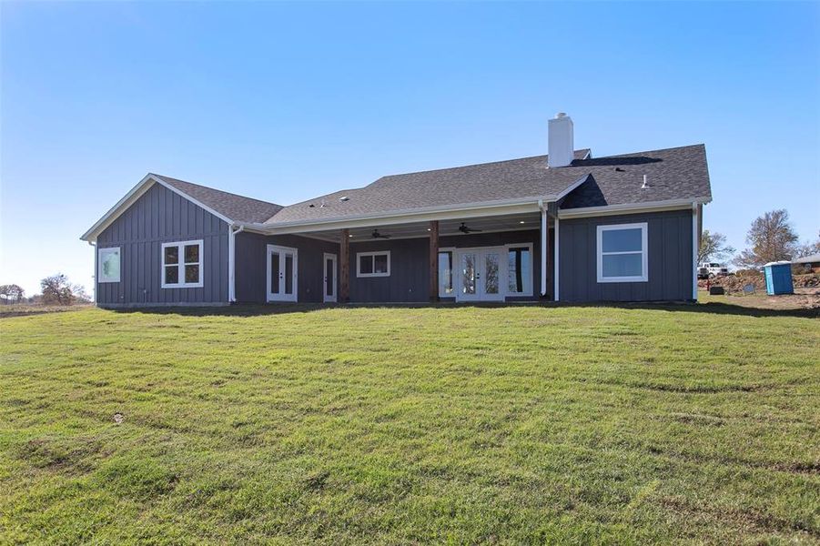 Back of property with french doors, a ceiling fan, a patio, a lawn, and a chimney