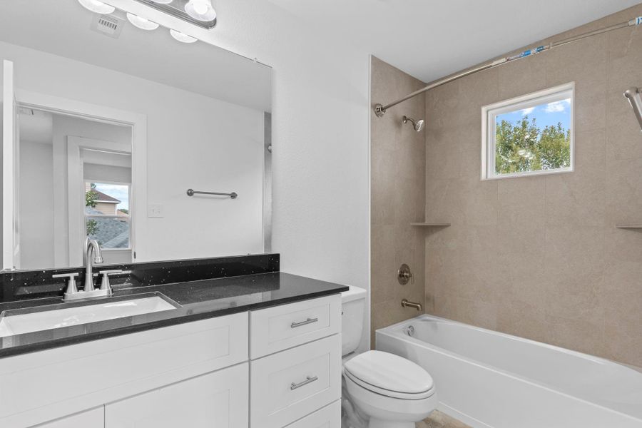 Your guest bathroom shines with custom shaker cabinetry, soft-close features, a deep undermount sink, and stunning quartz countertops. The tub/shower combo is finished with floor-to-ceiling tile, while a transom window brings in warm natural light. Truly an incredible home to call home! Your guest bathroom shines with custom shaker cabinetry, soft-close features, a deep undermount sink, and stunning quartz countertops. The tub/shower combo is finished with floor-to-ceiling tile, while a transom window brings in warm natural light. Truly an incredible home to call home!