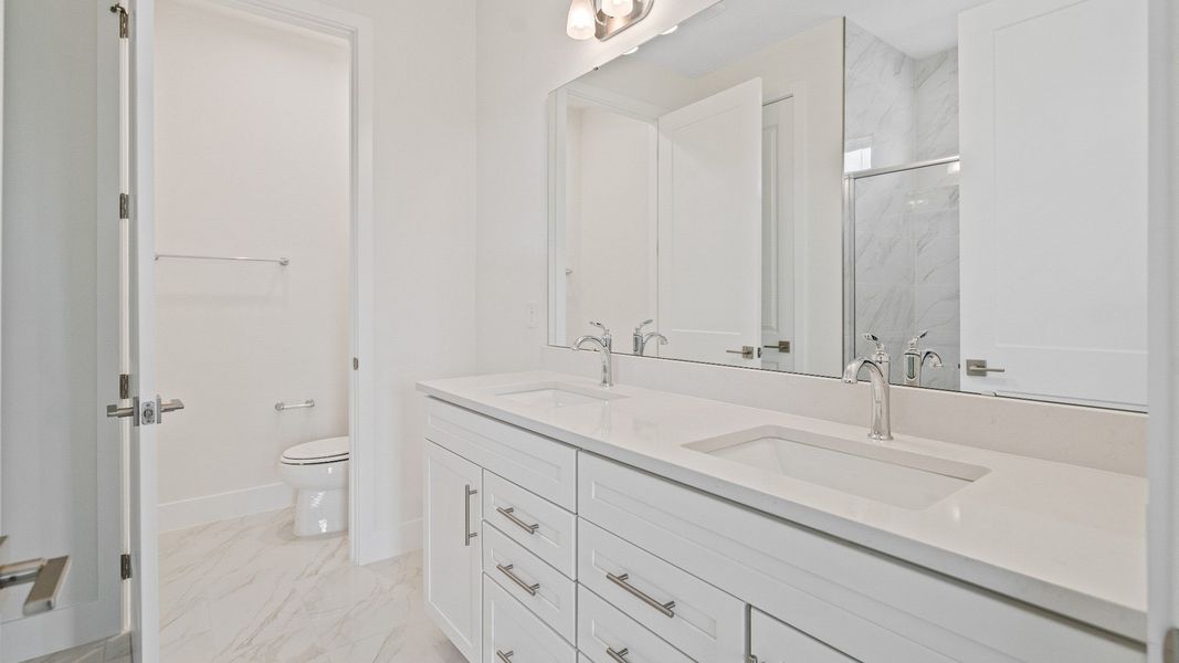 The Sweetgum Spacious and Bright first floor primary suite en-suite bath with dual sinks in Trailside Mount Dora by DRB Homes